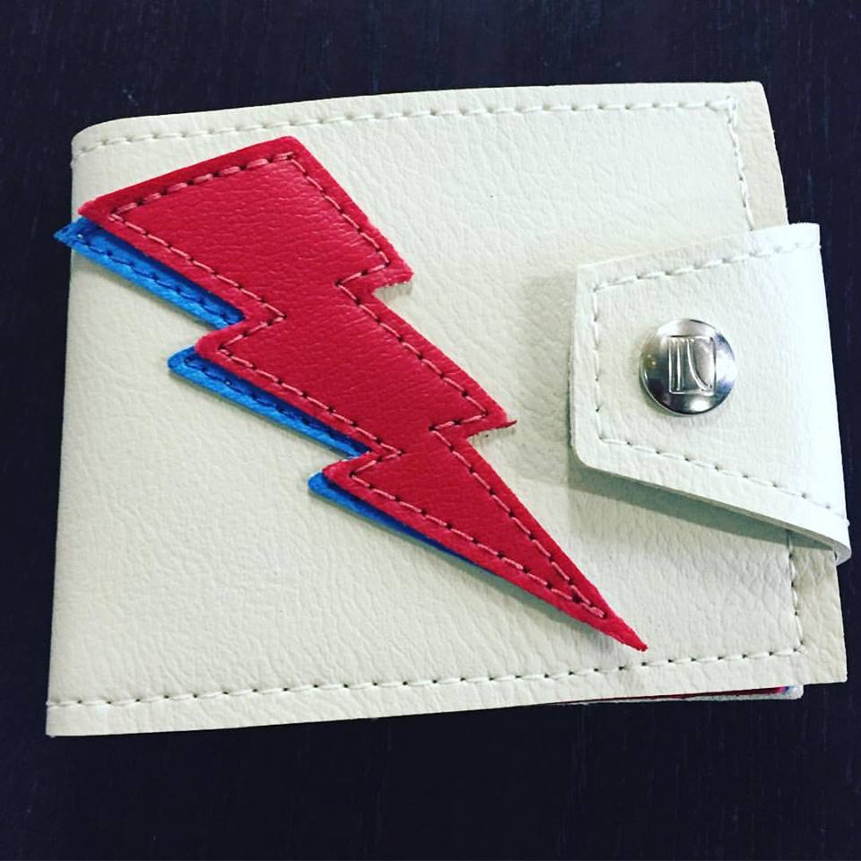 Close-up of the white wallet's snap closure and the lightning bolt appliqué stitching
