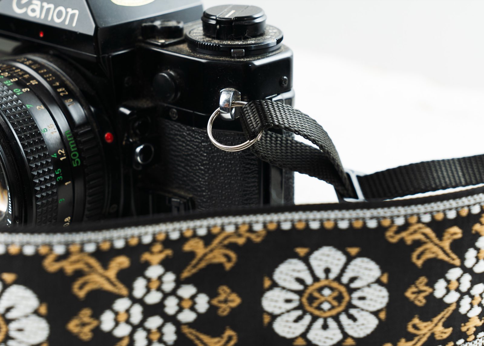 Camera strap webbing attached to the strap lug of a vintage Canon film camera
