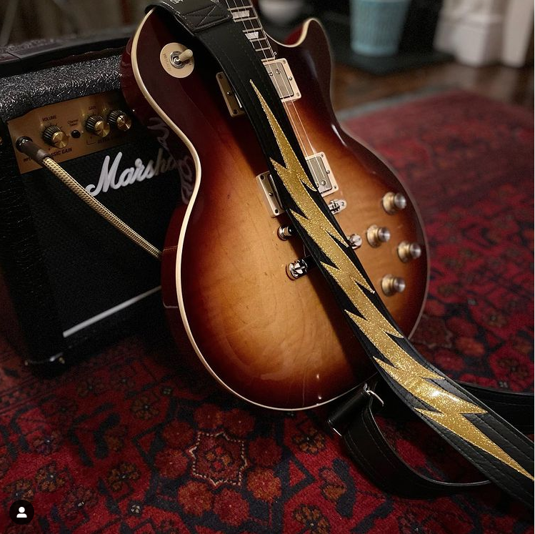Black Mega Bolt strap with a gold sparkle bolt, worn on a sunburst Les Paul