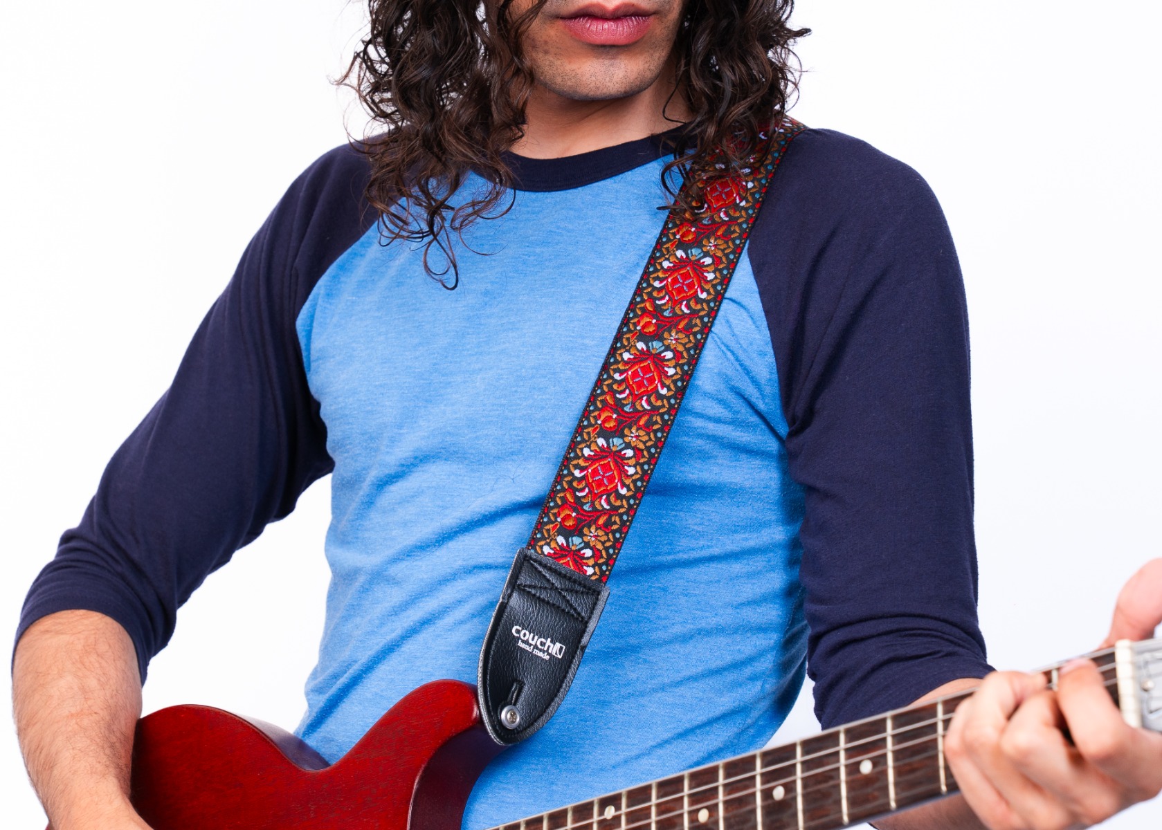 The Hendrix-style hippie weave strap worn on the shoulder with a red guitar