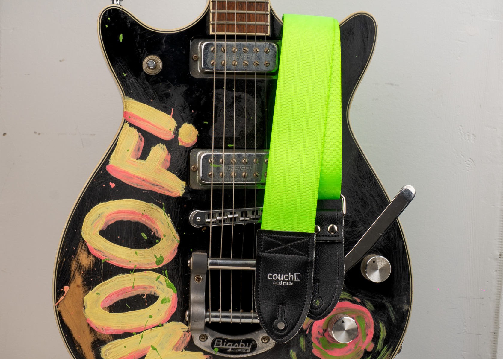 The neon green seatbelt guitar strap worn on a painted black electric guitar