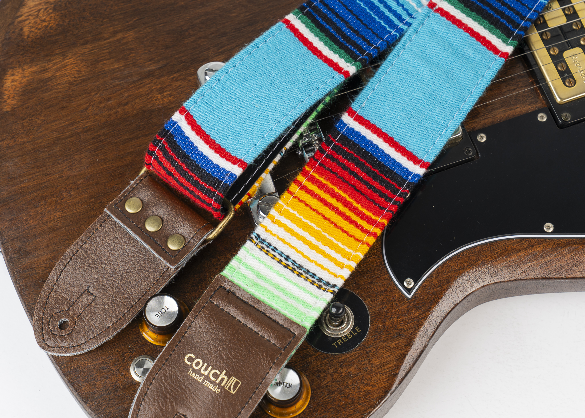 Brown vegan leather end tabs with aged bronze rivets on the blue serape strap