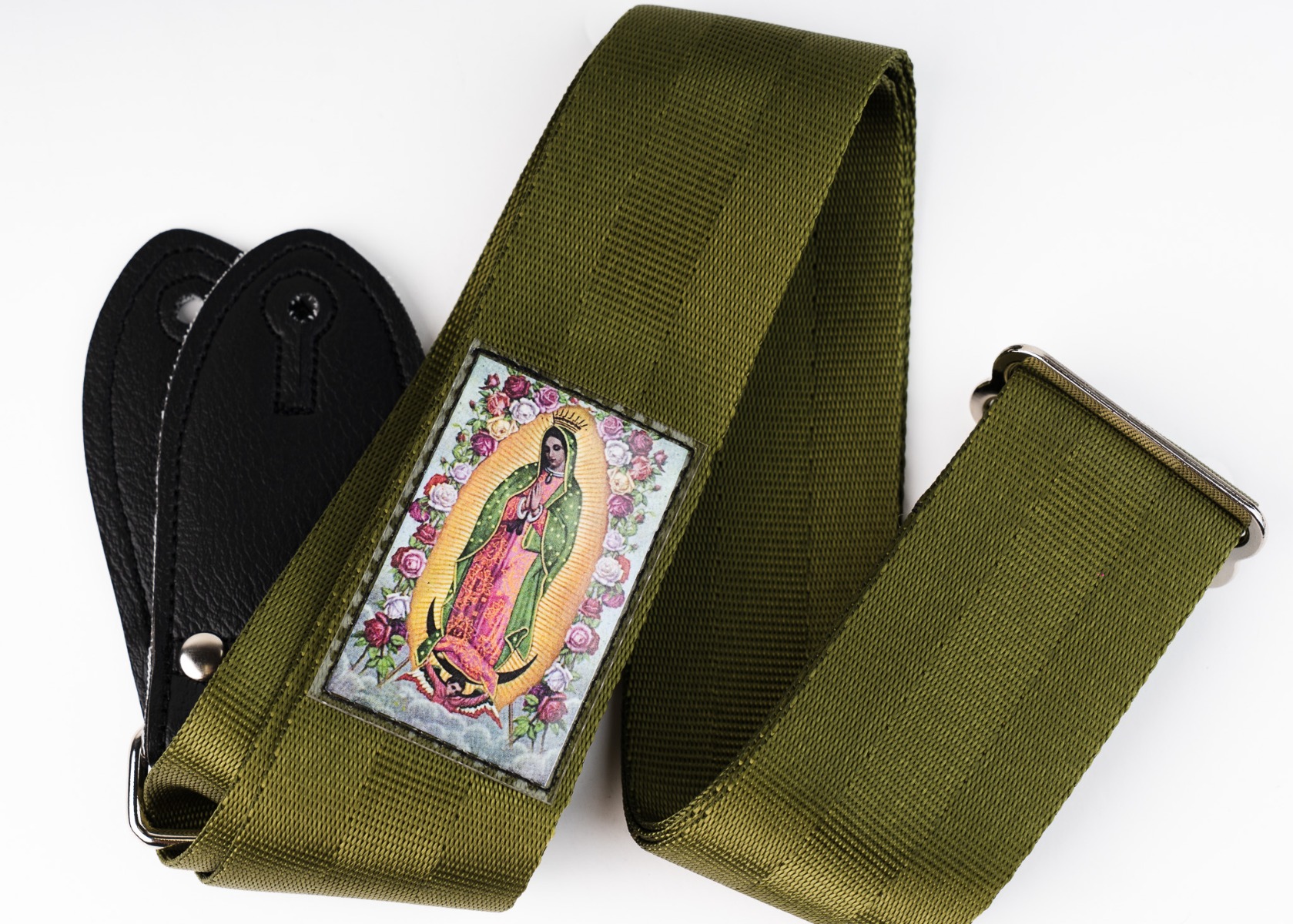 The Mary Guadalupe guitar strap in army green, showing the devotional image sealed under clear plastic