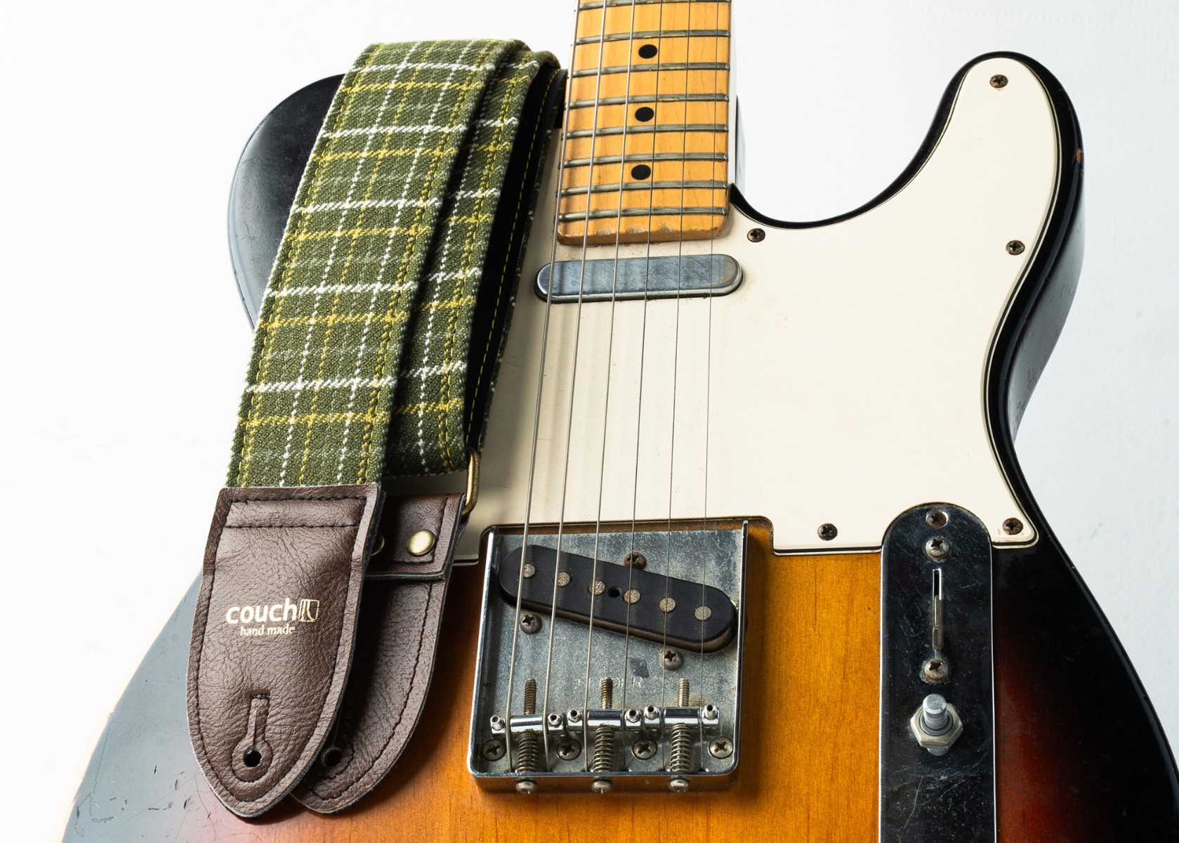 The olive plaid guitar strap worn on a sunburst Telecaster
