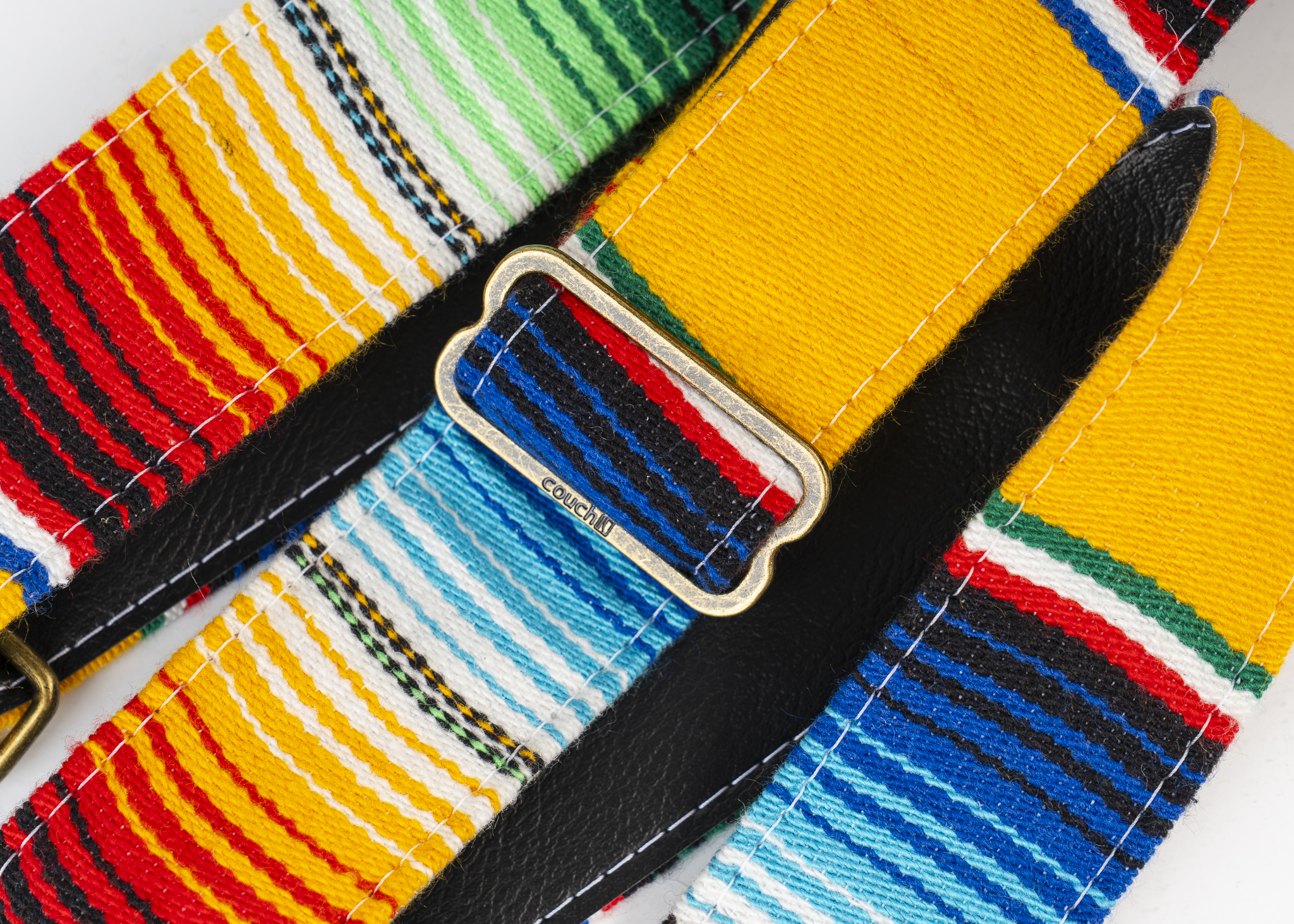 The aged bronze slide adjuster stamped with the Couch logo on the yellow serape strap