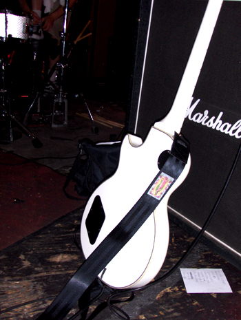 The Mary Guadalupe guitar strap resting on a white guitar backstage
