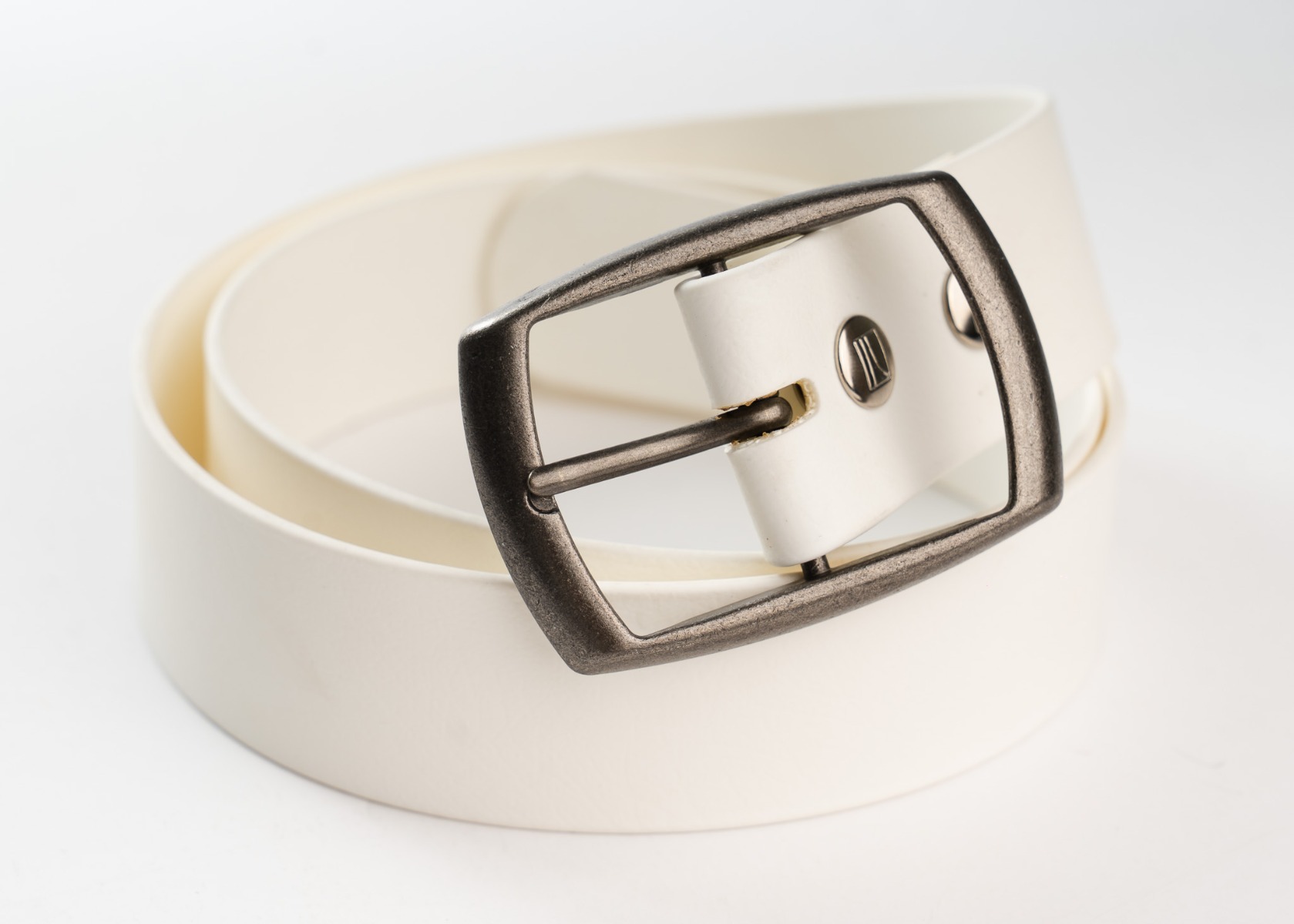 Close-up of the antique silver buckle and logo snap on the white belt