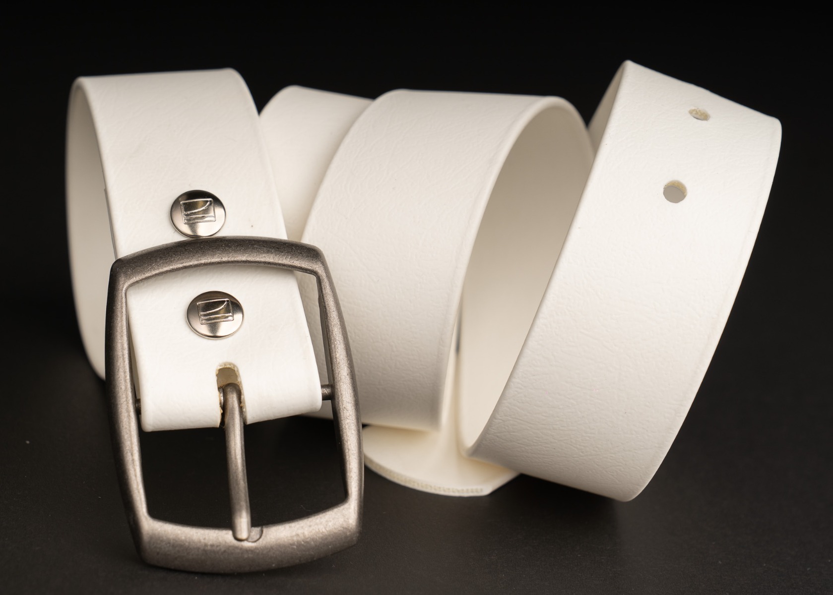 The coiled white BioThane belt showing its texture and Couch logo snaps