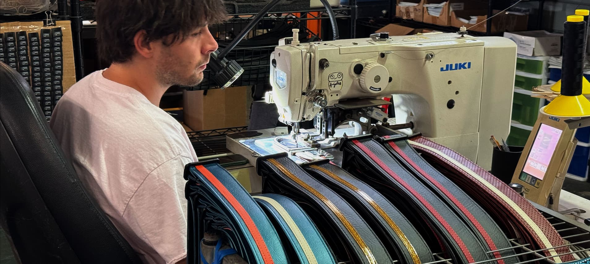Couch craftsman hand-sewing a row of strap end tabs on an industrial Juki sewing machine