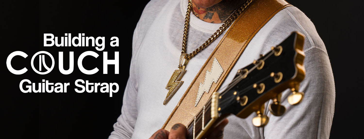 Musician wearing a gold glitter Couch guitar strap with a lightning bolt inlay, guitar headstock visible
